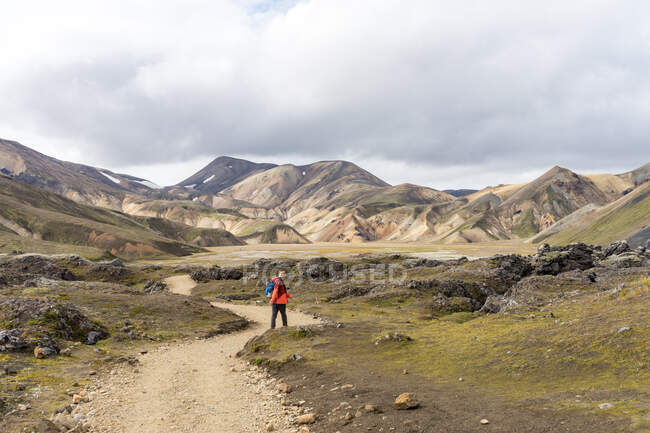 Caminante masculino caminando por el camino rocoso vacío en Islandia - foto de stock