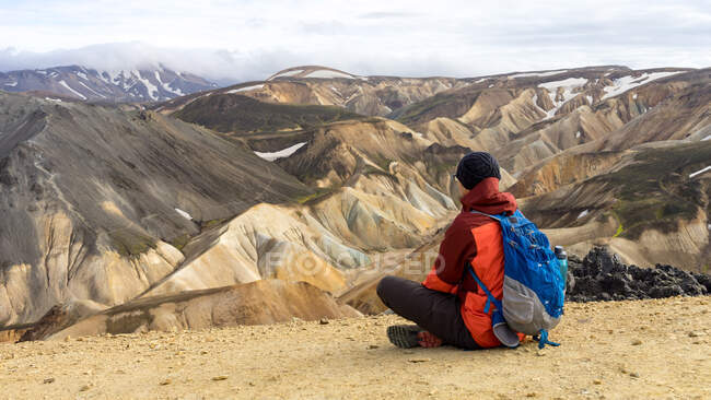 Randonneur masculin faisant une pause en regardant Landmannalaugar collines sablonneuses — Photo de stock