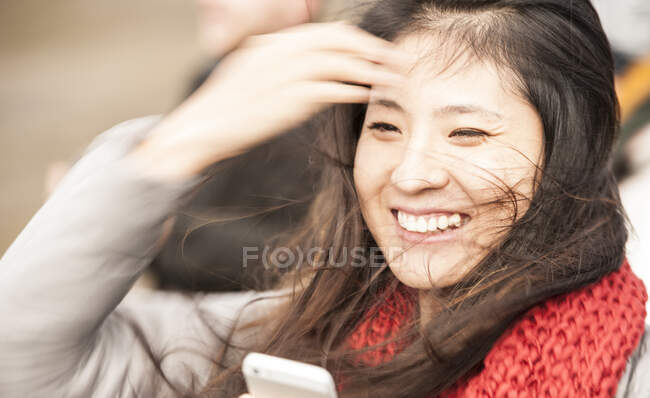 Schöne Frau schaut bei windigem Wetter auf ihr Handy — Stockfoto