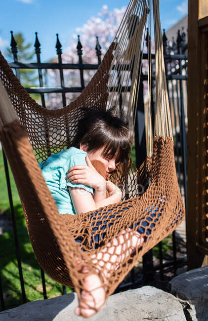 Young boy sleeping in a hammock in a backyard on a sunny day. — Stock Photo