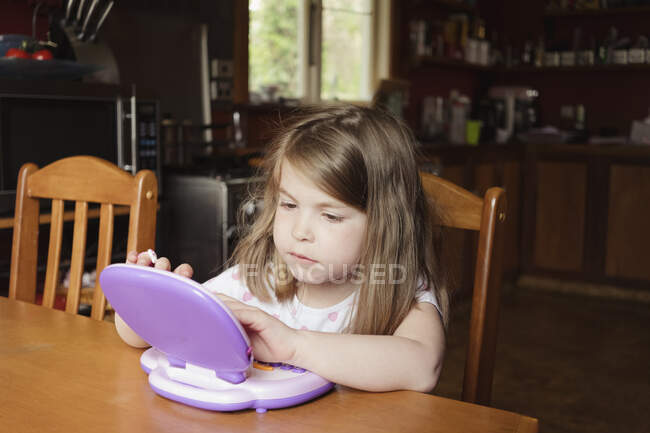Junges Mädchen sitzt und spielt auf Vorschultablette — Stockfoto