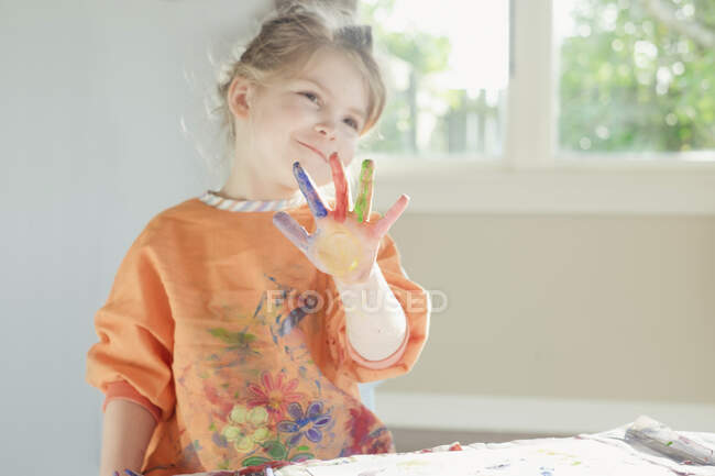Menina sorrindo com tinta na mão — Fotografia de Stock