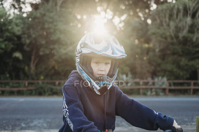 Jeune garçon portant un casque de moto regardant la caméra — Photo de stock