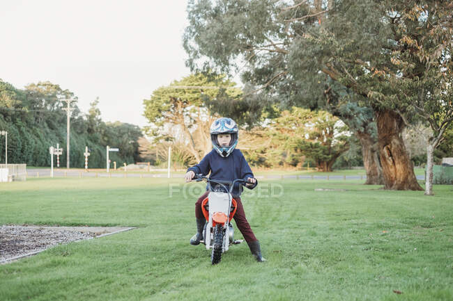 Jeune garçon assis sur une moto dans le parc — Photo de stock