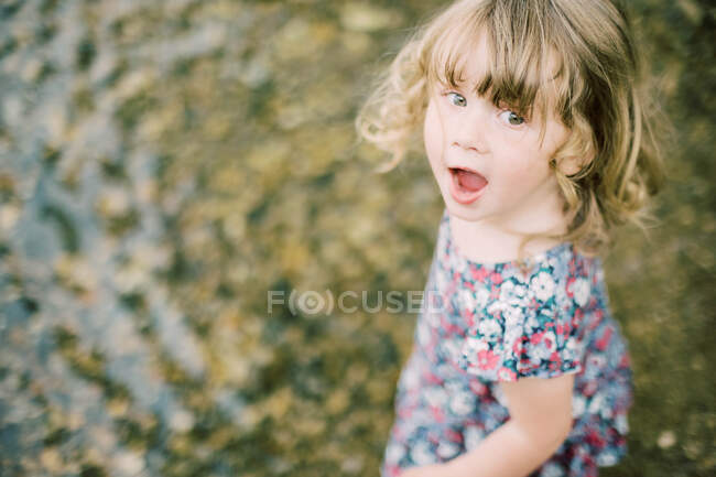 Una niñita emocionada por jugar en el lago - foto de stock