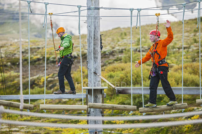 Dos hombres balanceándose en pista de obstáculos de cuerda alta en Islandia - foto de stock