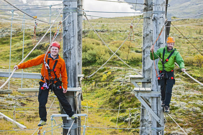 Two men balancing on high rope obstacle course in Iceland — Stock Photo