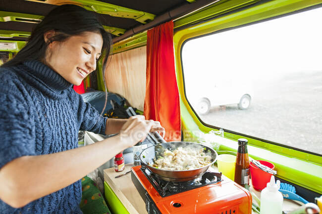 Woman cooking inside of camper van at remote location in Iceland — Stock Photo