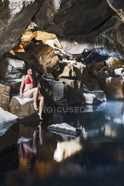 Mujer sentada en la cueva Grjotgja en el norte de Islandia - foto de stock