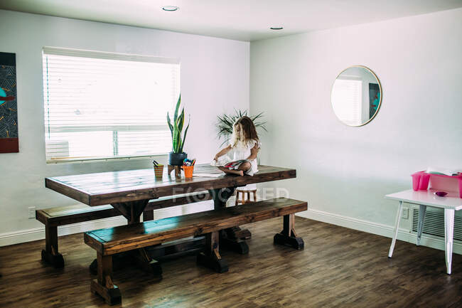 Giovane ragazza seduta sul tavolo a leggere da sola — Foto stock