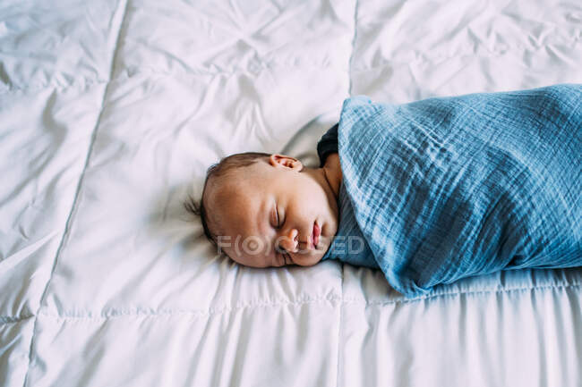 Над головою новонародженого малюка, що сидить на білому покритті. — стокове фото