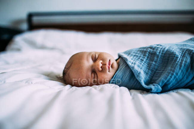 Close up of newborn sleeping on bed alone — Stock Photo
