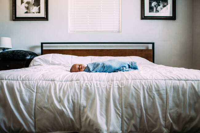 Новорожденный спит один на большой кровати — стоковое фото