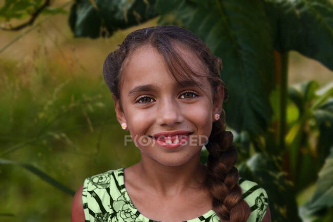 Fille souriante avec des dents de lait et tresse épaisse dans un parc — Photo de stock
