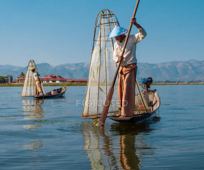 Dos pescadores que pescan con la red típica de Myanmar - foto de stock