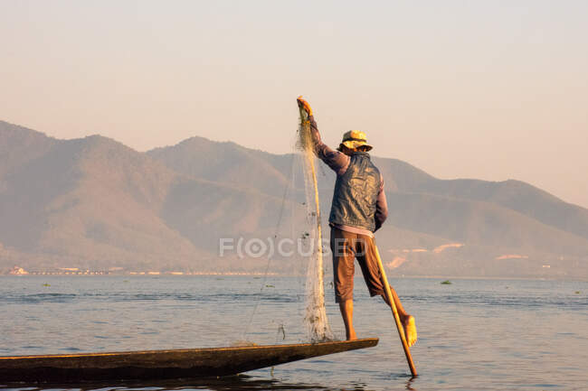 Fisherman balancing and fishing during sunset — Stock Photo