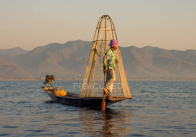 Рибалка ловить рибу під час заходу сонця. — стокове фото