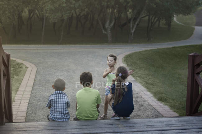 Дети играют на природе на закате девушка объясняет правила г — стоковое фото