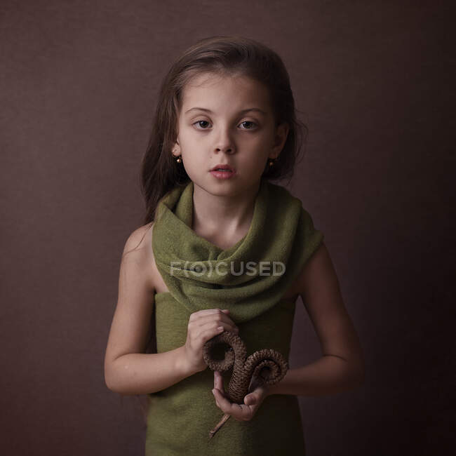 Дівчина на коричневому фоні тримає пальмовий лист, що означає зодіак — стокове фото