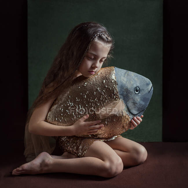 Une fille avec un nouvel ami un poisson est assis avec un poisson dans ses mains — Photo de stock