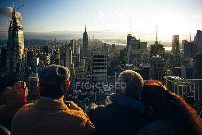 La gente ve desde rascacielos los edificios de Nueva York al atardecer y tomar fotos con el móvil, Estados Unidos - foto de stock