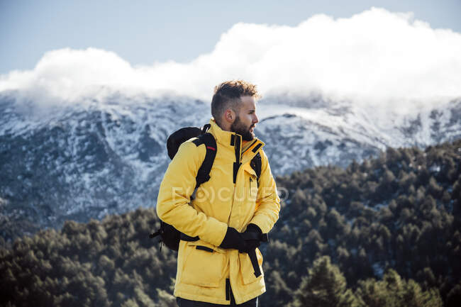 Jeune homme avec veste jaune et sac à dos dans les montagnes. — Photo de stock
