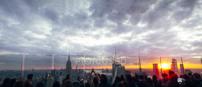 La gente observa desde los rascacielos los edificios de Nueva York al atardecer y - foto de stock