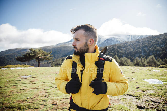 Молодой человек в желтой куртке и рюкзаке в горах. — стоковое фото