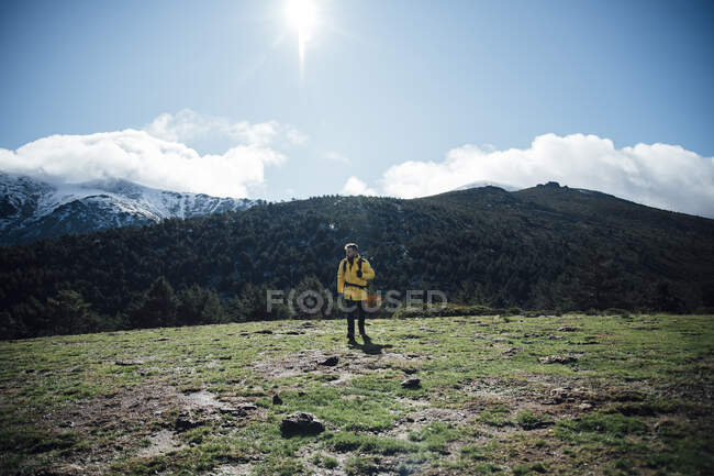 Молодой человек в желтой куртке и рюкзаке в горах. — стоковое фото
