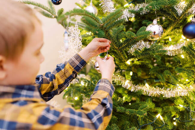 Menino colocando ornamentos em sua árvore de Natal — Fotografia de Stock