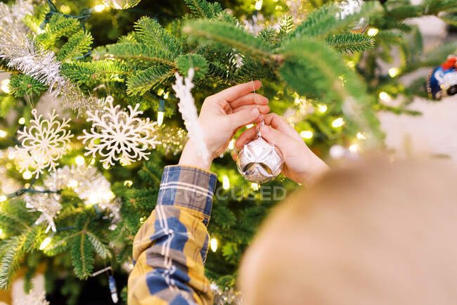 Маленький мальчик надевает украшения на свою елку — стоковое фото