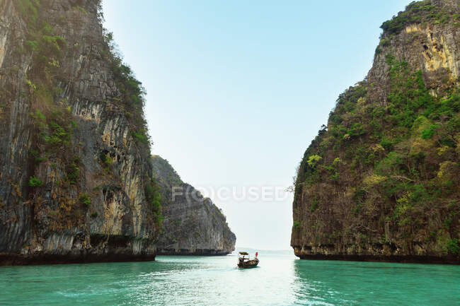 Paisaje de un barco navegando entre dos rocas con vegetación. - foto de stock