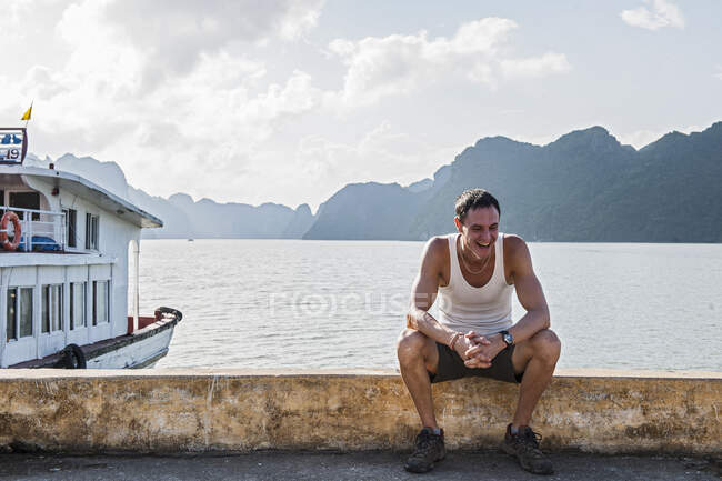 Человек, сидящий на пирсе в заливе Халонг во Вьетнаме — стоковое фото