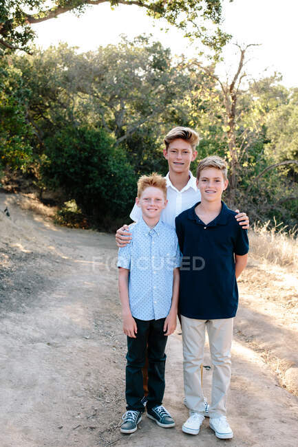 Drei Brüder lächeln draußen in der Natur für die Kamera — Stockfoto