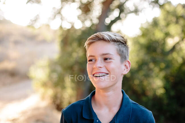 Портрет красивого молодого подростка, смотрящего и улыбающегося снаружи — стоковое фото
