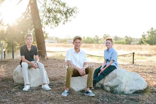 Retrato fora de três meninos sentados em grandes rochas — Fotografia de Stock