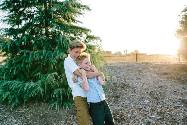 Irmão adolescente mais velho dá um abraço de estrangulamento ao irmãozinho — Fotografia de Stock