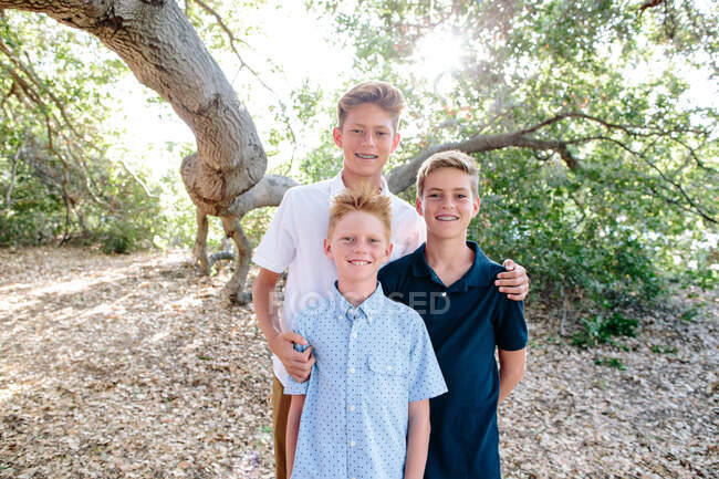 Retrato de três meninos sorrindo debaixo do dossel de um enorme carvalho — Fotografia de Stock