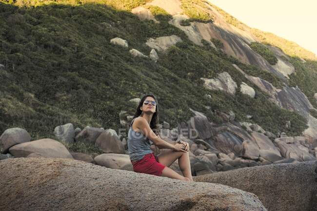 Hermosa mujer sentada en una piedra en el espacio natural - foto de stock