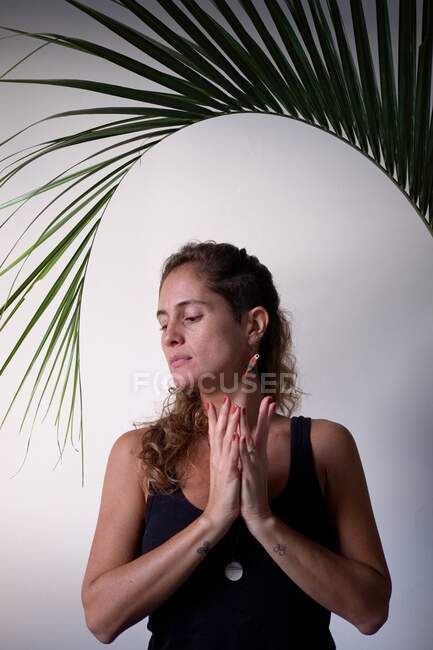 Schöne Frau praktiziert Yoga zu Hause mit Palmblatt — Stockfoto