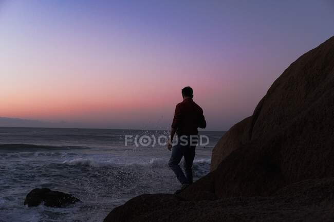 Чоловік стоїть біля узбережжя, спостерігаючи, як сходить сонце — стокове фото
