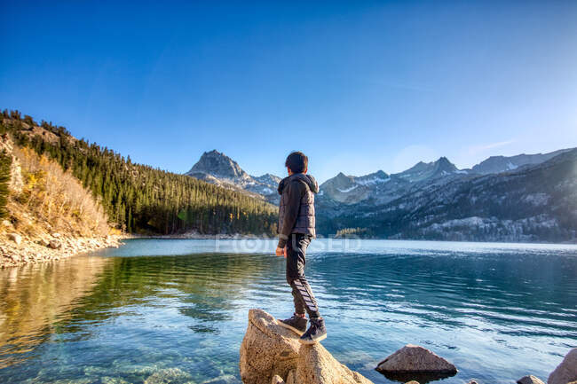 Rapaz a olhar para um lago nas Sierras, Califórnia. — Fotografia de Stock