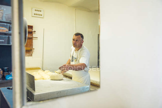 Hombre que pesa masa en una balanza en una pastelería en Belgrado, Serbia - foto de stock