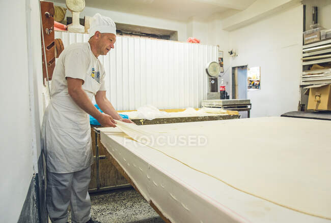 Baker Stretching Dough Across uma mesa em uma padaria em Belgrado, Sérvia — Fotografia de Stock