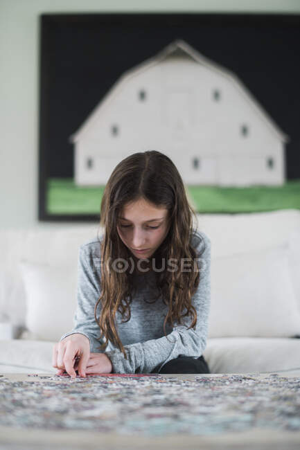 Young girl playing with a jigsaw puzzle inside — Stock Photo
