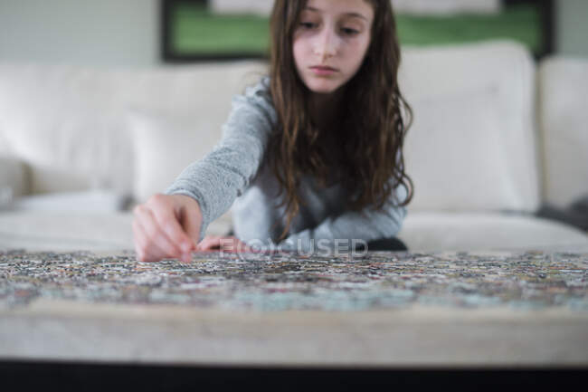 Молодая девушка работает над головоломкой в помещении — стоковое фото