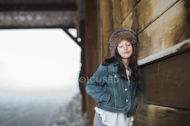 Girl in fur headband leaning against a bridge with eyes closed — Stock Photo
