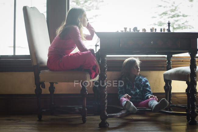 Meninas dentro olhando para uma janela em roupas de esqui — Fotografia de Stock