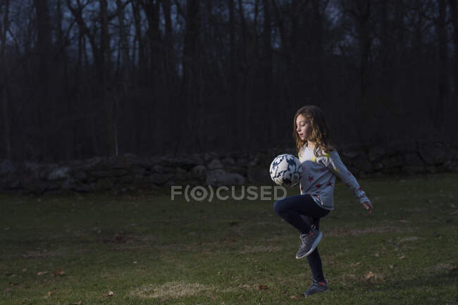 Mädchen spielt nachts draußen Fußball — Stockfoto