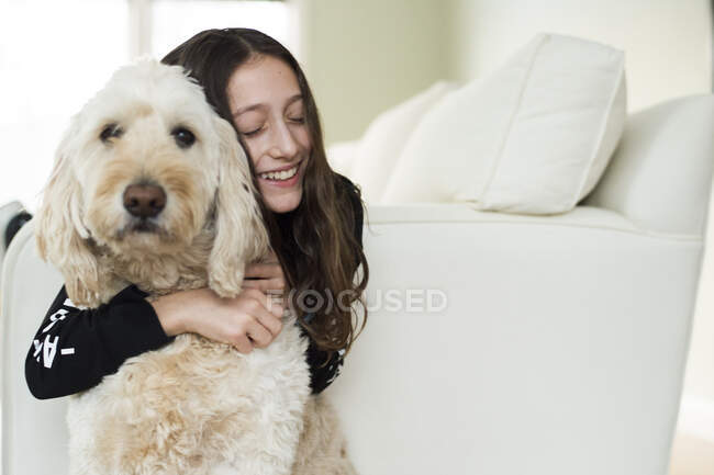Молода дівчина з собакою на білому дивані — стокове фото